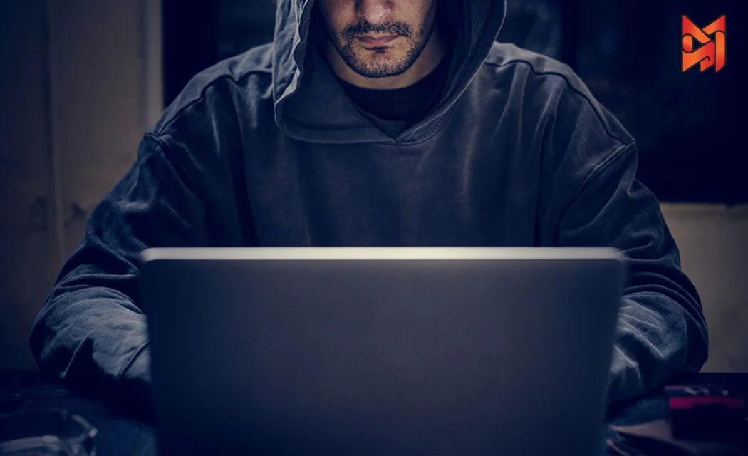 A person in a dark hoodie working on a laptop, symbolizing unethical Black Hat SEO practices.