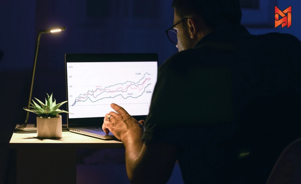 Focused individual studying business growth trends on a laptop, applying growth hacking techniques.
