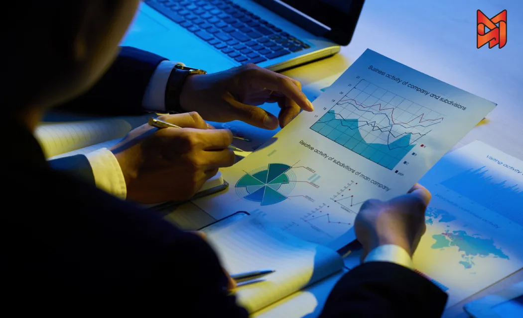Two people analyzing growth charts with a laptop, strategizing for business success.