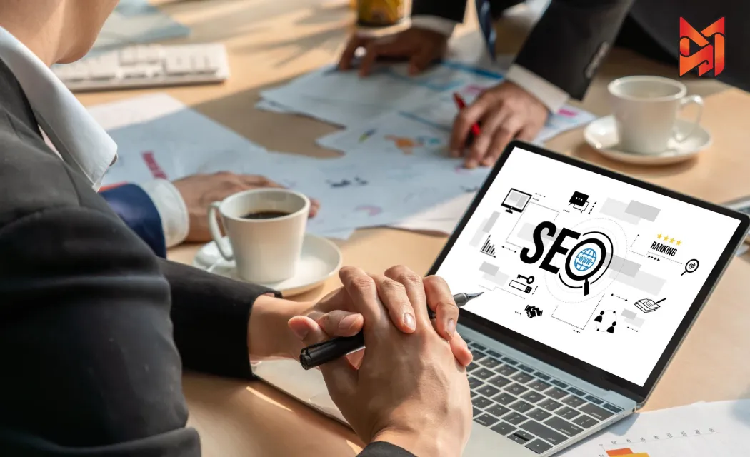 SEO experts collaborating at a table with a laptop showing SEO charts for website improvement.