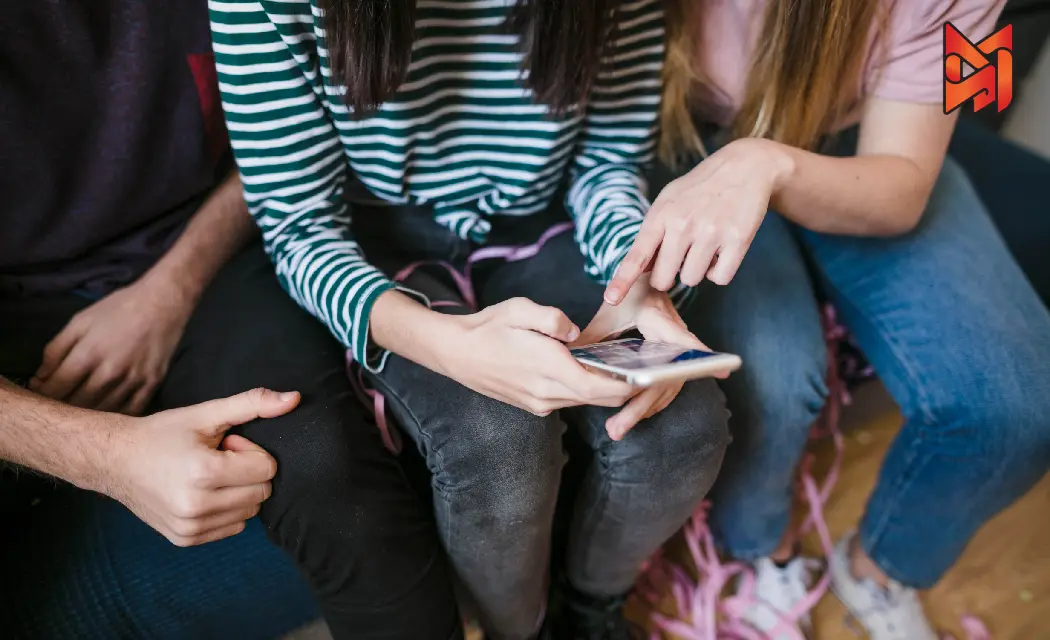 Gen Z friends engaging with a phone, highlighting the importance of connecting with them in marketing strategy.